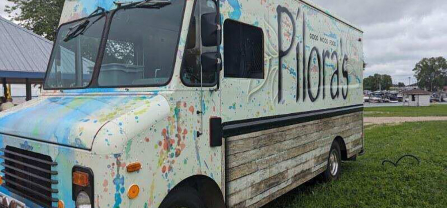 A white foodtruck with paint splatters on the side